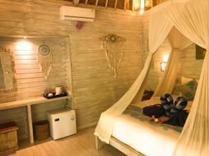 a bedroom with a canopy bed in a room with wooden walls at The Lucky Cottage in Nusa Lembongan