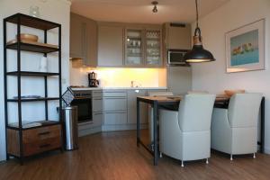 a kitchen with a table and some white chairs at Duinroos in Nes