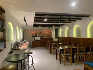 a dining room with tables and chairs and a kitchen at Courtyard Maldives in Huraa