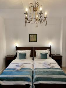 1 dormitorio con 2 camas y lámpara de araña en Pensiunea Charlotte Boutique en Bacău