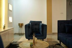 uma sala de estar com uma cadeira azul e uma mesa em Appartement cosy or bonapriso em Douala