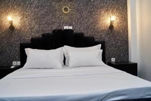 um quarto com uma cama com lençóis brancos e almofadas em Appartement cosy or bonapriso em Douala