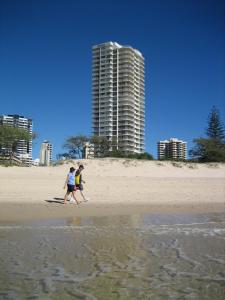 two people on a beach with a surfboard at Talisman Apartments in Gold Coast