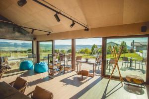 sala de estar con ventanas grandes, mesa y sillas en Natura Hill Panzió & Slow Food Fine Bistro en Zebegény