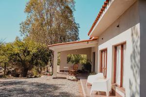 卡法亞特的住宿－EL PEDREGAL Casa en Cafayate，一座带白色椅子和树木的庭院