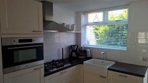 a kitchen with a stove and a sink and a window at House@Domburg in Domburg