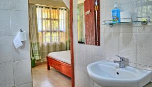 een badkamer met een wastafel, een bed en een spiegel bij Itibo Resort in Kisii