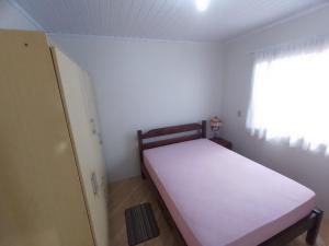 Habitación pequeña con cama y ventana en Casa Vânia, en Canela