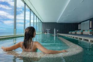 une femme est assise dans une piscine dans l'établissement VidaMar Resort Hotel Madeira - Dine Around Half Board, à Funchal