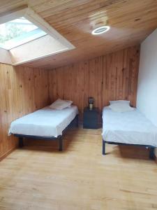 2 camas en una habitación con paredes de madera y ventana en La marMotte perchée, en Gap