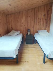 two beds in a room with wooden walls at La marMotte perchée in Gap