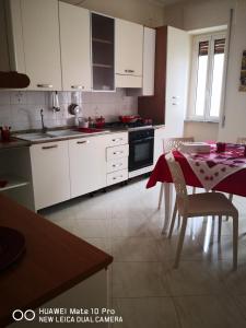 マテーラにあるCasa Maddalena familyの白いキャビネットとテーブル(テーブルクロス付)が備わるキッチン