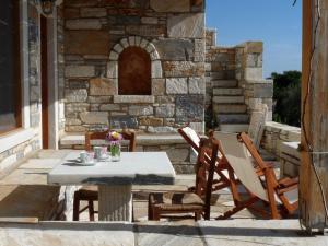 a table and chairs on a patio with a stone wall at Traditional stone-built cottages Azalas in Moutsouna Naxos