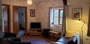 a living room with a couch and a television at Seven Stars- hot tub & garden with fabulous views. in Llandrindod Wells