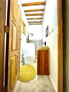 a bathroom with a toilet and a wooden door at Butterfly Apartment Zanzibar in Bwejuu