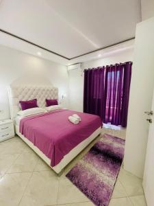a bedroom with a large bed and purple curtains at Queen Kodre Apartments in Ulcinj