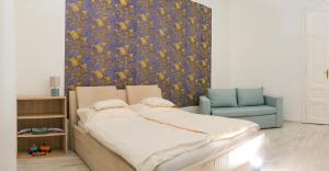 a bedroom with a bed and a blue chair at Sky Apartment in Debrecen