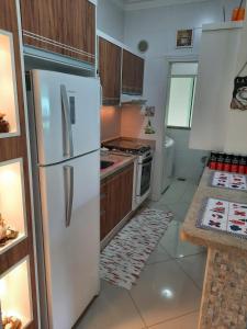 a kitchen with a white refrigerator and wooden cabinets at Amplo e confortável apto a 98 metros da praia de Bombinhas in Bombinhas