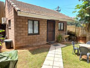 a small brick house with a table and chairs at Anne's Cottage in Durban
