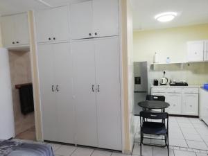 a kitchen with white cabinets and a table and a chair at Anne's Cottage in Durban