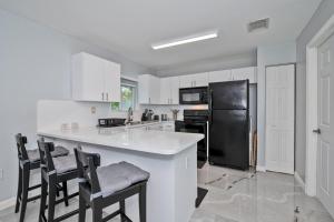 uma cozinha com armários brancos e um frigorífico preto em Hard Rock Hidden Gem! em Miami Gardens