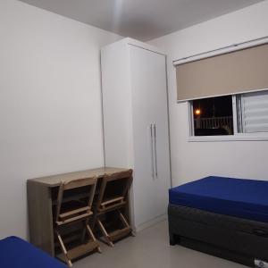 a bedroom with a bed and a desk and a window at Cristal da Vista Linda Apartamento 03 in Bertioga
