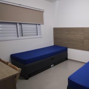 a room with a blue bed and a window at Cristal da Vista Linda Apartamento 03 in Bertioga