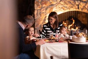 a man and woman sitting at a table with two babies at Hotel Borovi Forest Resort & Spa in Sjenica