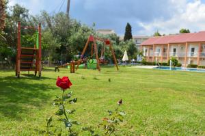 een rode roos in een park met een speeltuin bij Aggelos Family Hotel in Moraitika