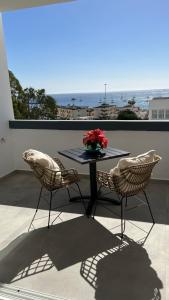een tafel met 2 stoelen en een vaas met bloemen op een balkon bij Boutique studio, sea views of Las Vistas and free wifi in Playa de las Americas