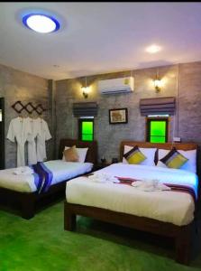 duas camas num quarto com luzes verdes em The Chater@kangkud em Ban Muang Kut