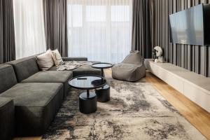 a living room with a couch and a tv at Mandala A Designer Penthouse with Free Private Parking, near Mall Coresi in Braşov