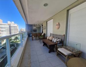 - un balcon avec un canapé et des chaises dans un bâtiment dans l'établissement Riviera São Lourenço Excelente Apartamento e Local, à Riviera de São Lourenço