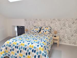 een slaapkamer met een bed met een blauw en geel dekbed bij gîte de l'atelier 15 personnes in Grazac