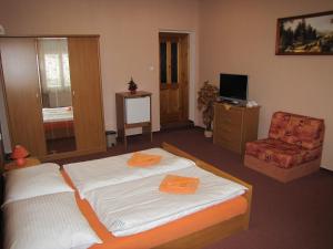 a bedroom with two beds and a chair and a television at Penzion Aldo in Karviná