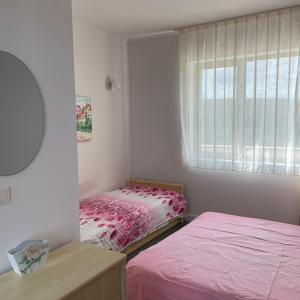 a bedroom with two beds and a window with pink sheets at YooBulgaria-Obzor SP apartments in Obzor
