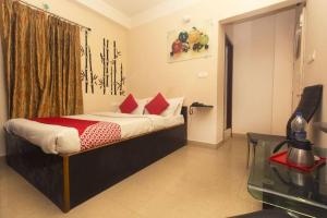 a bedroom with a bed with red pillows and a glass table at Skyline Lodge in Siliguri