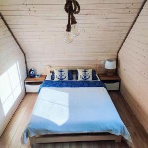 sypialnia z dużym łóżkiem z niebieską pościelą i poduszkami w obiekcie Domki Halo Morze w Jastrzębiej Górze