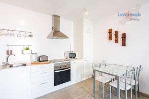 kuchnia z białymi szafkami i stołem z krzesłami w obiekcie Vivienda Vacacional Casa Las Cucharas w Costa Teguise