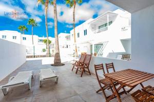 patio z drewnianym stołem, krzesłami i palmami w obiekcie Vivienda Vacacional Casa Las Cucharas w Costa Teguise