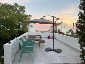 a patio with chairs and an umbrella on a balcony at Wave watch terrace apartment in Benalmádena