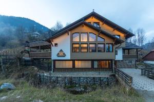 una casa en una colina con montañas en el fondo en Ranger Chalet, en Moieciu de Sus