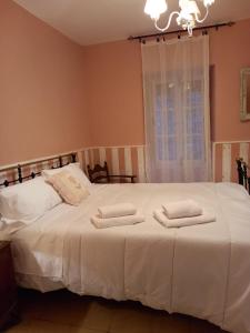 1 dormitorio con 1 cama blanca y 2 toallas en Casa Rural Las Raíces, Sierra de San Vicente en San Román