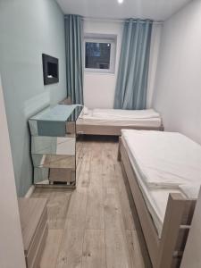 Habitación pequeña con 2 camas y TV. en Apartament Turkusowy, en Jelenia Góra