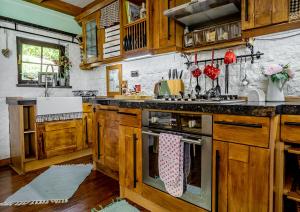 cocina con armarios de madera y horno con fogones en Amazing Milk and Honey cottage with hill views en Novi Marof