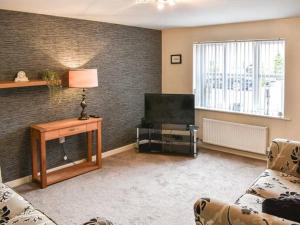 a living room with a couch and a television at ThreeStorey Townhouse - Free parking in Normanton