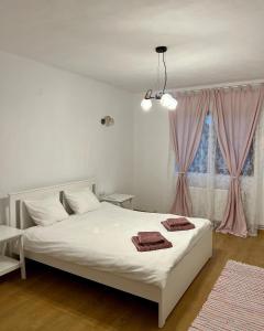 a bedroom with a white bed and a window at Casuta de la Munte in Sfodea
