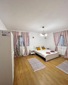 a bedroom with a white bed and pink curtains at Casuta de la Munte in Sfodea