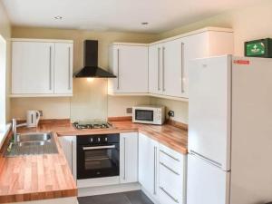a kitchen with white cabinets and a stove and a microwave at ThreeStorey Townhouse - Free parking in Normanton
