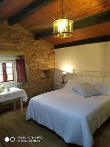 a bedroom with a white bed and a stone wall at Casita en Domaio - Moaña in Moaña